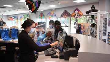 Cashier and customers at the Fly Buy Gift Shop store counter